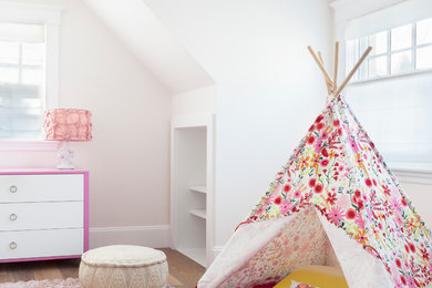 Example of a beach style girl medium tone wood floor and beige floor kids' room design in New York with white walls