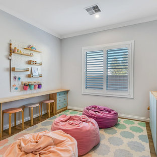 This is an example of a contemporary gender-neutral kids' playroom for kids 4-10 years old in Other with grey walls, medium hardwood floors and brown floor.
