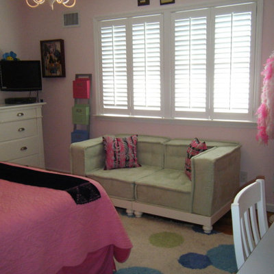 Inspiration for a mid-sized timeless girl medium tone wood floor kids' room remodel in New York with pink walls
