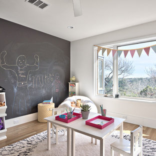 Example of a danish gender-neutral light wood floor and beige floor kids' room design in Austin with white walls
