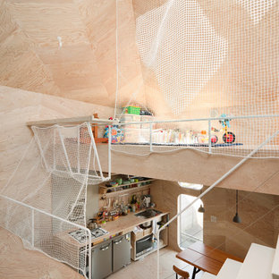 Esempio di una piccola cameretta per bambini da 4 a 10 anni industriale con pareti beige, pavimento in compensato e pavimento beige