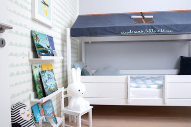 Modelo de dormitorio infantil de 1 a 3 años actual de tamaño medio con paredes grises, suelo de madera en tonos medios y suelo beige