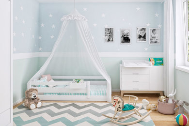 Modelo de dormitorio infantil de 1 a 3 años actual pequeño con paredes verdes y suelo de madera clara