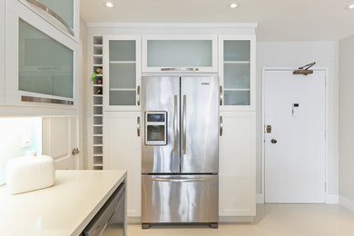 Eat-in kitchen - mid-sized modern galley ceramic tile eat-in kitchen idea in Miami with a drop-in sink, flat-panel cabinets, white cabinets, quartz countertops, white backsplash, cement tile backsplash and black appliances
