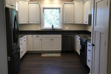 Enclosed kitchen - mid-sized traditional u-shaped vinyl floor and brown floor enclosed kitchen idea in Columbus with an undermount sink, raised-panel cabinets, white cabinets, granite countertops, black appliances and no island