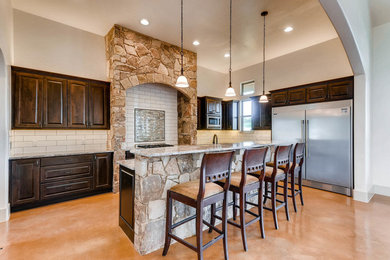 Mid-sized elegant l-shaped concrete floor and beige floor kitchen photo in Austin with an undermount sink, raised-panel cabinets, dark wood cabinets, granite countertops, white backsplash, subway tile backsplash, stainless steel appliances and an island