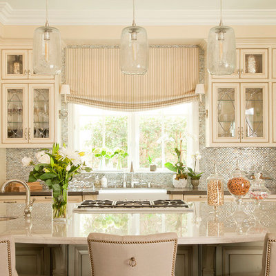 Elegant kitchen photo in Los Angeles with a farmhouse sink, beaded inset cabinets, beige cabinets, metallic backsplash, mosaic tile backsplash, stainless steel appliances and beige countertops