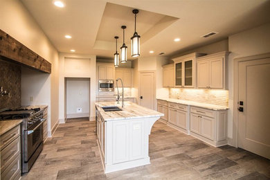 Mid-sized elegant u-shaped medium tone wood floor and brown floor open concept kitchen photo in New Orleans with an undermount sink, recessed-panel cabinets, gray cabinets, quartz countertops, beige backsplash, ceramic backsplash, stainless steel appliances and an island