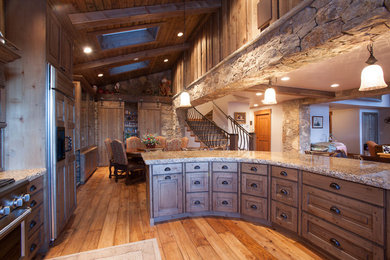 Inspiration for a mid-sized rustic single-wall medium tone wood floor eat-in kitchen remodel in Denver with recessed-panel cabinets, medium tone wood cabinets, granite countertops, brown backsplash, stone slab backsplash, paneled appliances and an island