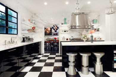 This is an example of a large traditional l-shaped kitchen/diner in Los Angeles with a built-in sink, flat-panel cabinets, black cabinets, marble worktops, white splashback, marble splashback, black appliances, marble flooring, an island and black floors.