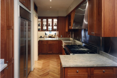 Mid-sized trendy u-shaped medium tone wood floor and beige floor enclosed kitchen photo in New York with a farmhouse sink, shaker cabinets, dark wood cabinets, granite countertops, gray backsplash, metal backsplash and stainless steel appliances