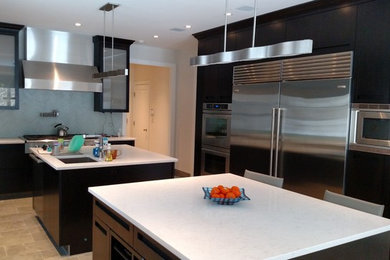 Example of a minimalist eat-in kitchen design in New York with stainless steel appliances and two islands