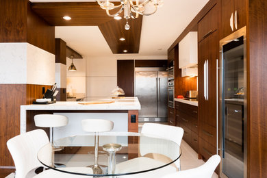 トロントにある高級な広いコンテンポラリースタイルのおしゃれなキッチン (アンダーカウンターシンク、フラットパネル扉のキャビネット、中間色木目調キャビネット、珪岩カウンター、白いキッチンパネル、クオーツストーンのキッチンパネル、シルバーの調理設備、セラミックタイルの床、白い床、白いキッチンカウンター) の写真