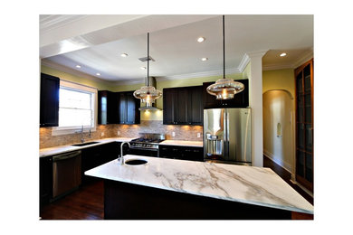 Example of a transitional l-shaped eat-in kitchen design in New Orleans with an undermount sink, shaker cabinets, distressed cabinets, marble countertops, beige backsplash, stone tile backsplash and stainless steel appliances
