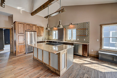 Inspiration for a rustic l-shaped medium tone wood floor open concept kitchen remodel in New York with an undermount sink, raised-panel cabinets, distressed cabinets, quartzite countertops, beige backsplash, subway tile backsplash, stainless steel appliances and an island