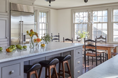 Inspiration for a mid-sized cottage u-shaped dark wood floor eat-in kitchen remodel in New York with a farmhouse sink, flat-panel cabinets, gray cabinets, marble countertops, stainless steel appliances and an island