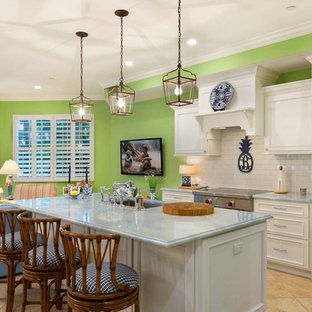 This is an example of a mid-sized beach style single-wall open plan kitchen in Miami with an undermount sink, recessed-panel cabinets, white cabinets, marble benchtops, white splashback, brick splashback, stainless steel appliances, ceramic floors, with island, beige floor and blue benchtop.