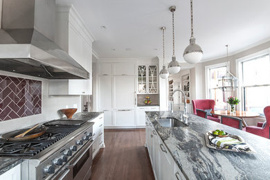 Medium tone wood floor kitchen photo in Boston with an undermount sink, white cabinets, soapstone countertops, white backsplash and stainless steel appliances