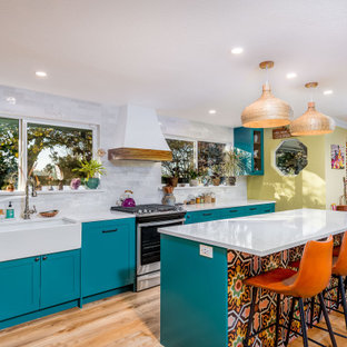 Immagine di una grande cucina tropicale con lavello stile country, ante in stile shaker, ante blu, paraspruzzi grigio, paraspruzzi con piastrelle diamantate, parquet chiaro, isola, pavimento beige e top bianco