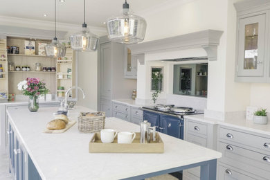Medium sized traditional u-shaped enclosed kitchen in Other with a belfast sink, beaded cabinets, blue cabinets, quartz worktops, glass sheet splashback, an island, beige floors and white worktops.