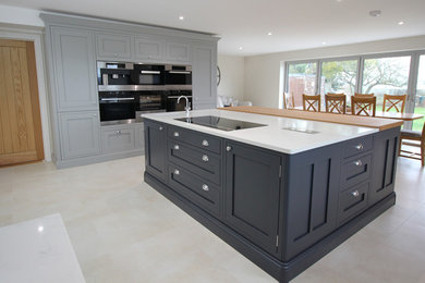 Inspiration for a large traditional l-shaped kitchen/diner in West Midlands with an integrated sink, shaker cabinets, quartz worktops, white splashback, stainless steel appliances, ceramic flooring, an island, beige floors and white worktops.