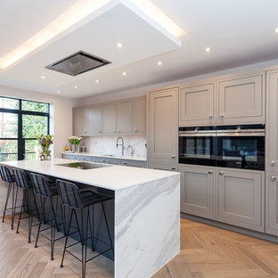 Immagine di una cucina design di medie dimensioni con lavello integrato, ante in stile shaker, ante grigie, top in quarzite, paraspruzzi bianco, paraspruzzi in marmo, elettrodomestici da incasso e isola