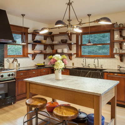 Eat-in kitchen - huge craftsman l-shaped light wood floor eat-in kitchen idea in Portland with raised-panel cabinets, soapstone countertops, white backsplash, subway tile backsplash, black appliances, an island, an integrated sink and medium tone wood cabinets