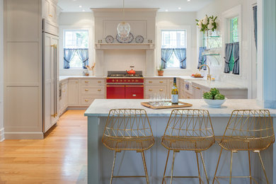 Example of a large transitional u-shaped light wood floor and brown floor eat-in kitchen design in New York with a farmhouse sink, a peninsula, recessed-panel cabinets, white cabinets, marble countertops, white backsplash, subway tile backsplash and paneled appliances