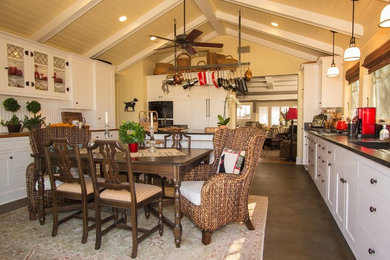 Example of a mid-sized cottage concrete floor open concept kitchen design in San Diego with beaded inset cabinets, white cabinets, solid surface countertops, white backsplash, an island, an undermount sink, wood backsplash and black appliances
