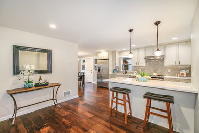 Inspiration for a mid-sized craftsman galley medium tone wood floor and brown floor eat-in kitchen remodel in Seattle with a single-bowl sink, flat-panel cabinets, white cabinets, quartz countertops, gray backsplash, ceramic backsplash, stainless steel appliances, a peninsula and white countertops