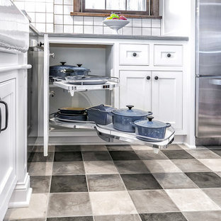 Photo of a small traditional l-shaped separate kitchen in Minneapolis with a farmhouse sink, flat-panel cabinets, white cabinets, quartz benchtops, white splashback, porcelain splashback, stainless steel appliances, ceramic floors, no island and grey floor.