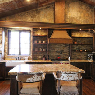 Design ideas for a mid-sized country u-shaped eat-in kitchen in Austin with a farmhouse sink, louvered cabinets, distressed cabinets, granite benchtops, multi-coloured splashback, stone tile splashback, panelled appliances, medium hardwood floors and with island.