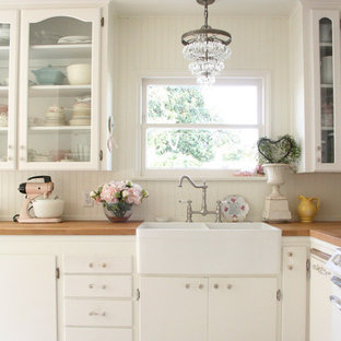 Immagine di una cucina stile shabby con lavello stile country, ante di vetro, ante bianche, top in legno e paraspruzzi bianco