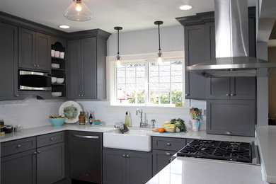 Mid-sized minimalist l-shaped dark wood floor eat-in kitchen photo in Milwaukee with a farmhouse sink, stainless steel appliances, shaker cabinets, white backsplash, subway tile backsplash, a peninsula, gray cabinets and quartz countertops