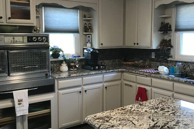 Diseño de cocina moderna de tamaño medio con encimera de granito, salpicadero verde, electrodomésticos de acero inoxidable, una isla y suelo gris