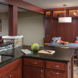 Inspiration for a mid-sized midcentury galley open plan kitchen in Columbus with an undermount sink, flat-panel cabinets, dark wood cabinets, granite benchtops, grey splashback, glass tile splashback, stainless steel appliances, vinyl floors and a peninsula.