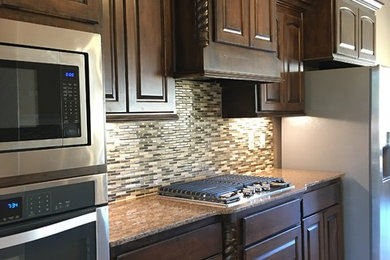 Example of a mid-sized classic single-wall travertine floor enclosed kitchen design in Austin with an undermount sink, beaded inset cabinets, dark wood cabinets, granite countertops, multicolored backsplash, matchstick tile backsplash, stainless steel appliances and a peninsula