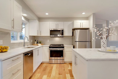 Example of a small minimalist l-shaped medium tone wood floor and brown floor eat-in kitchen design in Portland with an undermount sink, shaker cabinets, white cabinets, quartz countertops, gray backsplash, subway tile backsplash, stainless steel appliances and an island