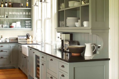 Example of a cottage l-shaped medium tone wood floor eat-in kitchen design in New York with a farmhouse sink, shaker cabinets, gray cabinets, granite countertops, white backsplash, subway tile backsplash, paneled appliances and an island