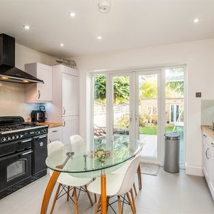 Inspiration for a medium sized contemporary galley kitchen/diner in Hertfordshire with shaker cabinets, white cabinets, wood worktops, no island, brown worktops, a built-in sink, multi-coloured splashback, glass tiled splashback, integrated appliances, porcelain flooring and grey floors.