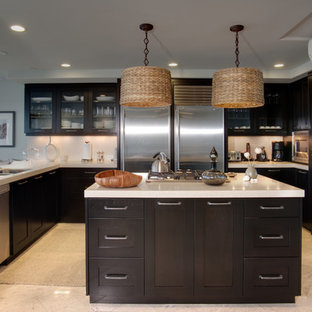 Idée de décoration pour une grand cuisine ethnique en U avec un évier 2 bacs, un placard à porte shaker, des portes de placard noires, un plan de travail en quartz modifié, un électroménager en acier inoxydable, un sol en carrelage de porcelaine, un îlot central, un sol beige et un plan de travail beige.