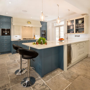 Photo of a large traditional kitchen in Cornwall with a submerged sink, beige splashback, stainless steel appliances, grey floors, white worktops, shaker cabinets, blue cabinets and a breakfast bar.