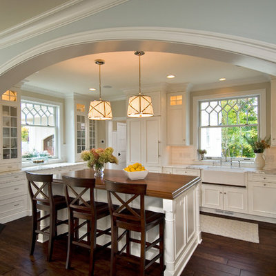 Example of a classic kitchen design in New York with a farmhouse sink, wood countertops and recessed-panel cabinets