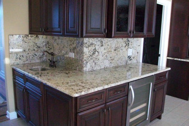 Example of a mid-sized kitchen design in Chicago with an undermount sink, recessed-panel cabinets, dark wood cabinets, granite countertops, beige backsplash, stone slab backsplash and stainless steel appliances