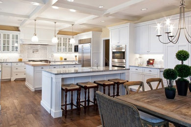 Foto de cocina clásica con electrodomésticos de acero inoxidable, dos o más islas, armarios con paneles empotrados y barras de cocina