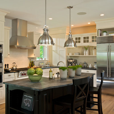Example of a transitional l-shaped kitchen design in New York with a farmhouse sink, shaker cabinets, white cabinets, white backsplash, subway tile backsplash and stainless steel appliances