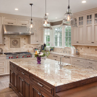 Foto de cocina tradicional con armarios con paneles con relieve, puertas de armario beige, salpicadero beige, electrodomésticos de acero inoxidable y salpicadero de piedra caliza
