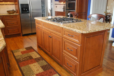 Example of a mid-sized classic u-shaped medium tone wood floor eat-in kitchen design in Philadelphia with a double-bowl sink, raised-panel cabinets, medium tone wood cabinets, granite countertops, white backsplash, subway tile backsplash, stainless steel appliances and an island