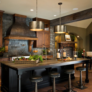 Inspiration for a country galley eat-in kitchen in New York with raised-panel cabinets, dark wood cabinets, black splashback, stainless steel appliances, dark hardwood floors, with island and slate splashback.