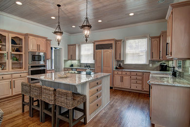 Klassische Wohnküche in U-Form mit Landhausspüle, profilierten Schrankfronten, hellen Holzschränken, Küchengeräten aus Edelstahl, braunem Holzboden, Kücheninsel und Granit-Arbeitsplatte in Charleston